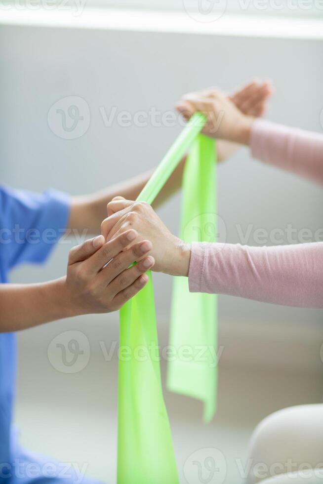 female doctor using elastic bands help patient regain muscle movement after recuperating from muscle injury and wants rehabilitate her be able use her normal daily life by practicing physical therapy photo