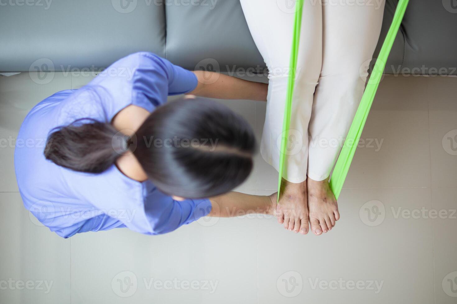 female doctor using elastic bands help patient regain muscle movement after recuperating from muscle injury and wants rehabilitate her be able use her normal daily life by practicing physical therapy photo