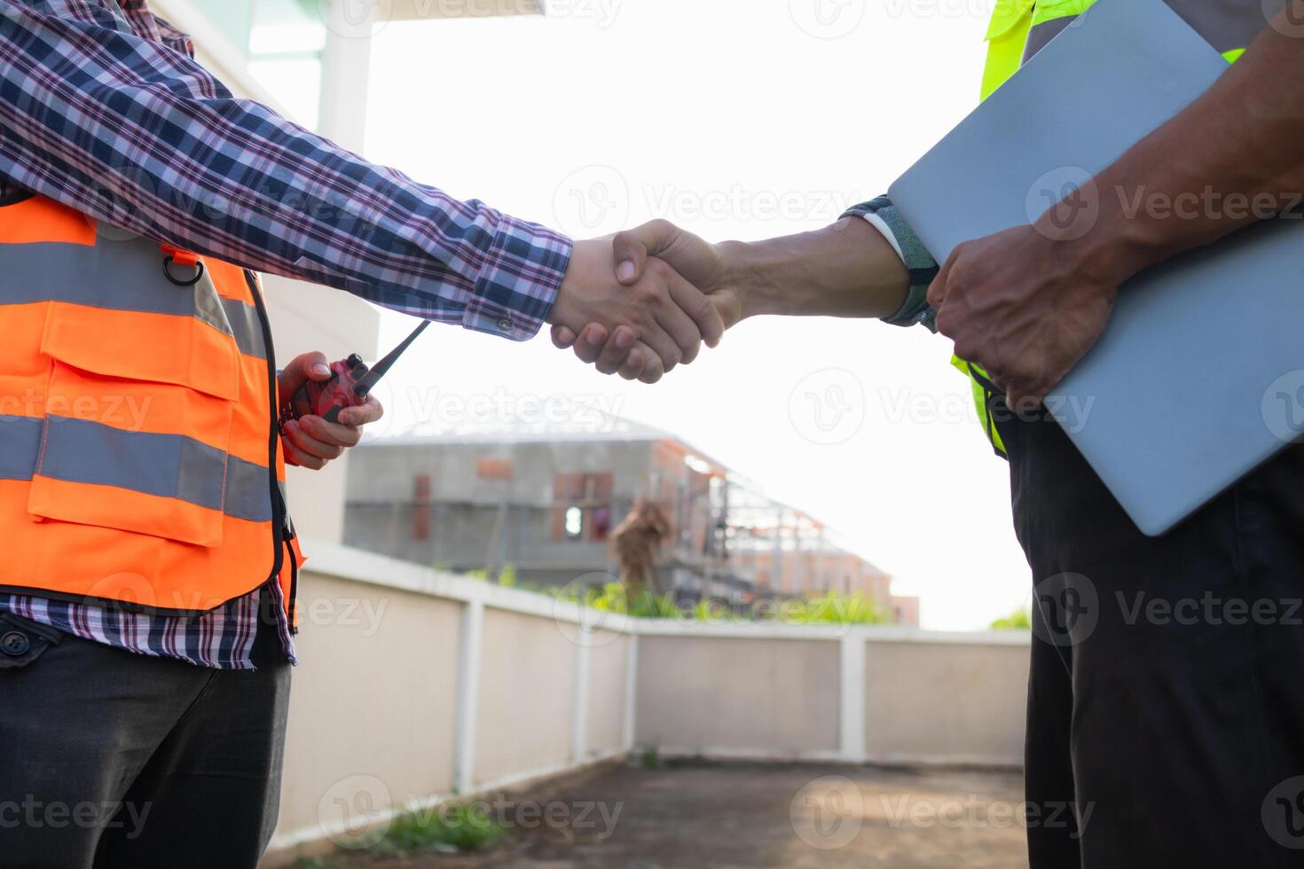 Behind the scenes foreman wearing reflective vest and hard hat inspects construction site to ensure construction meets engineering team's design plans and for the beauty and safety of residents. photo