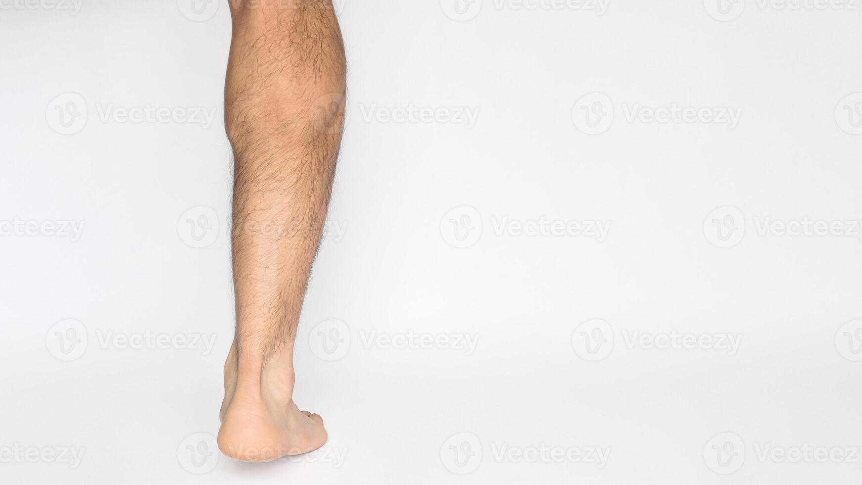 Foot and leg of an adult male seen from behind with a white background and space for text on the right. Heel, Achilles tendon, ankles, and calf photo