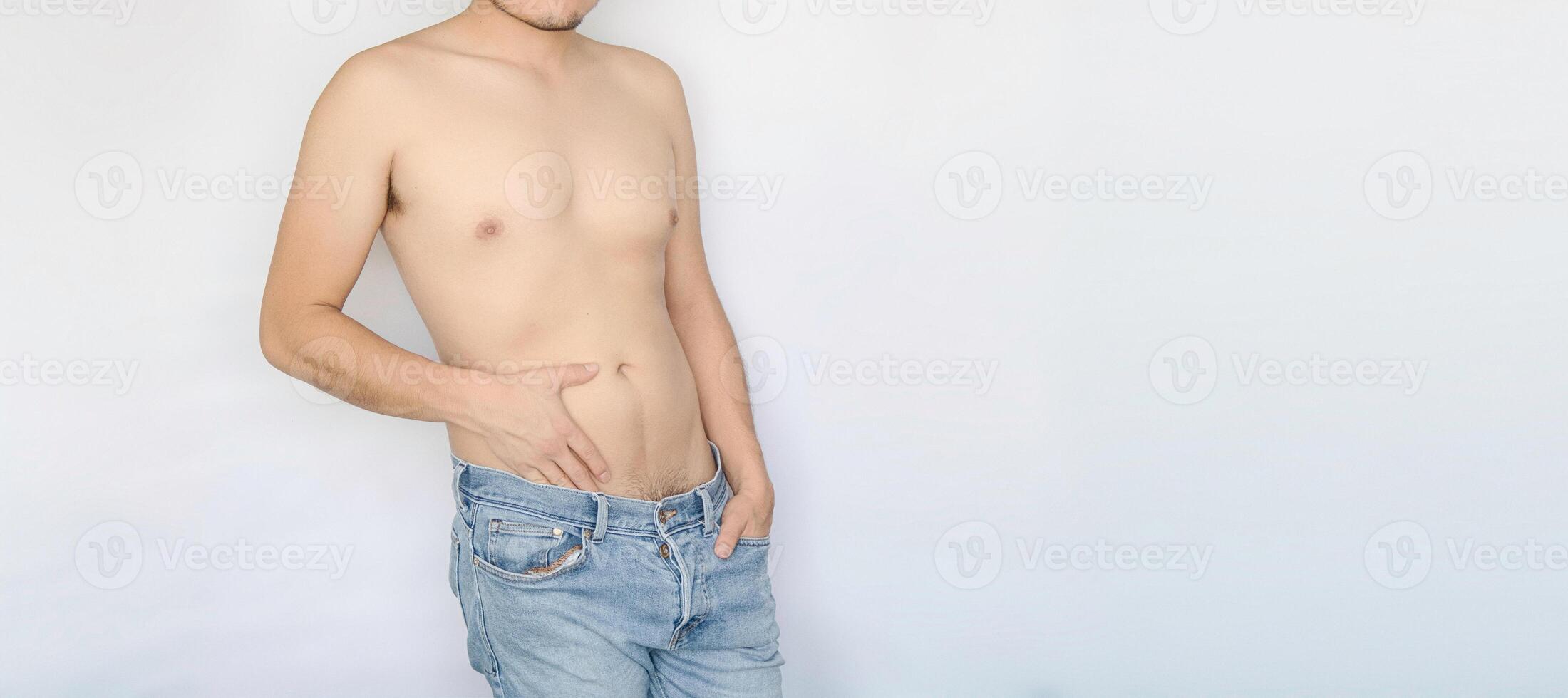 Man displaying his torso with blue jeans, white background, and space for text. Sexuality, masculinity, intimate areas. photo