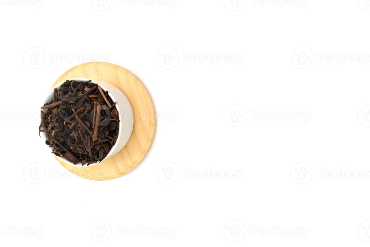 Dry black tea in round bowl isolated on white background photo
