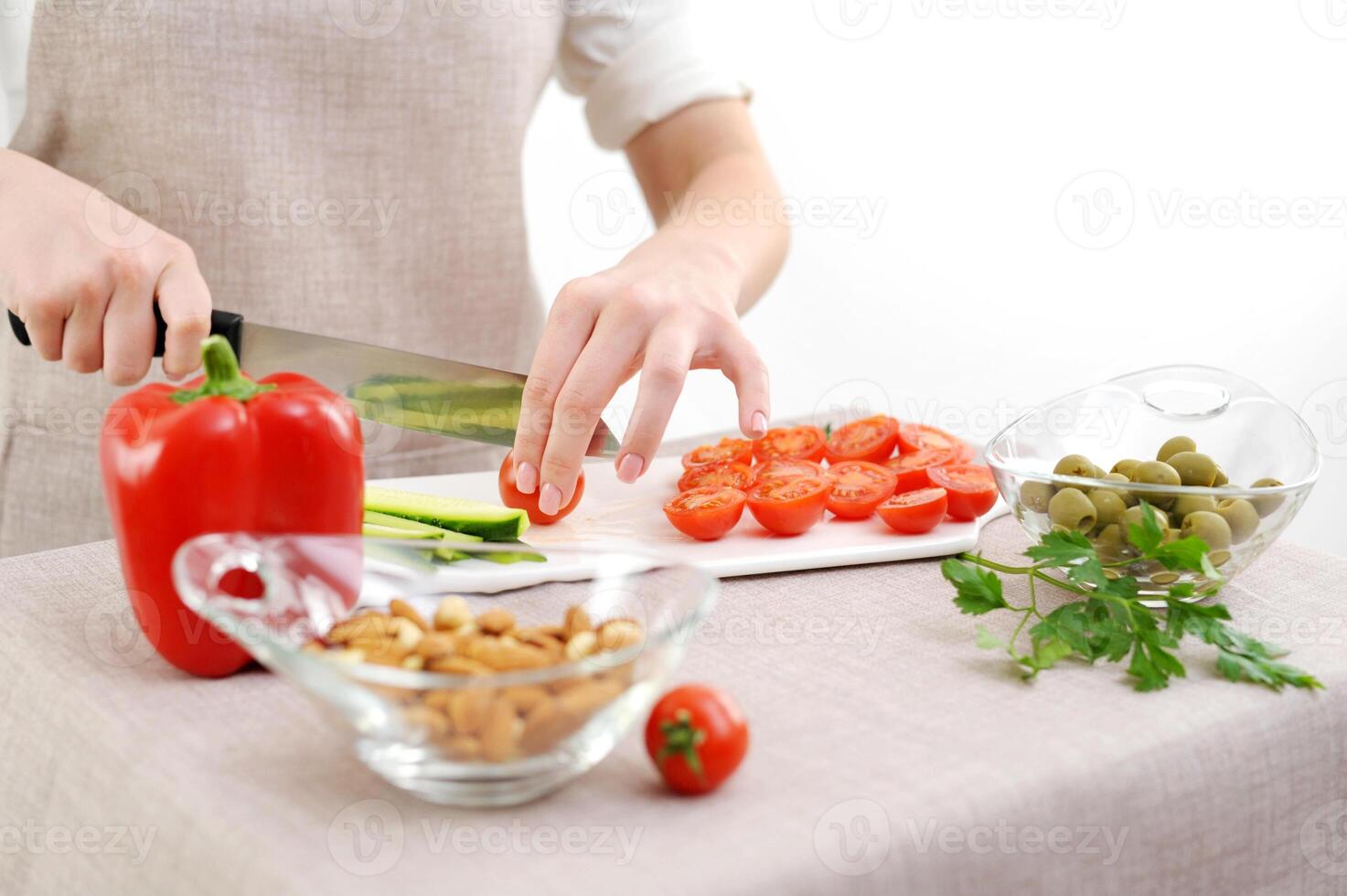 right side tomatoes sliced left cucumbers white porcelain board gentle manicure young female hand Healthy eating, dieting concept. High angle view of female hands cutting cucumber in the kitchen photo