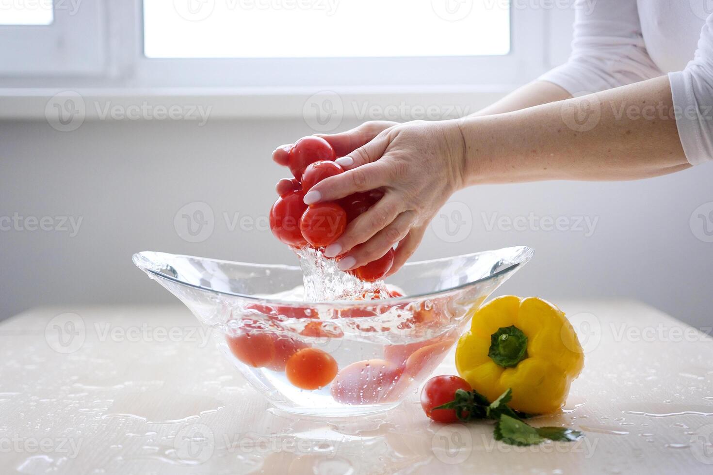 Super Slow Motion Shot of Flying Fresh Tomatoes with Water Splashing on White Background water in kitchen in morning under faucet. Preparing vegetables for making delicious veggie salad at home. photo