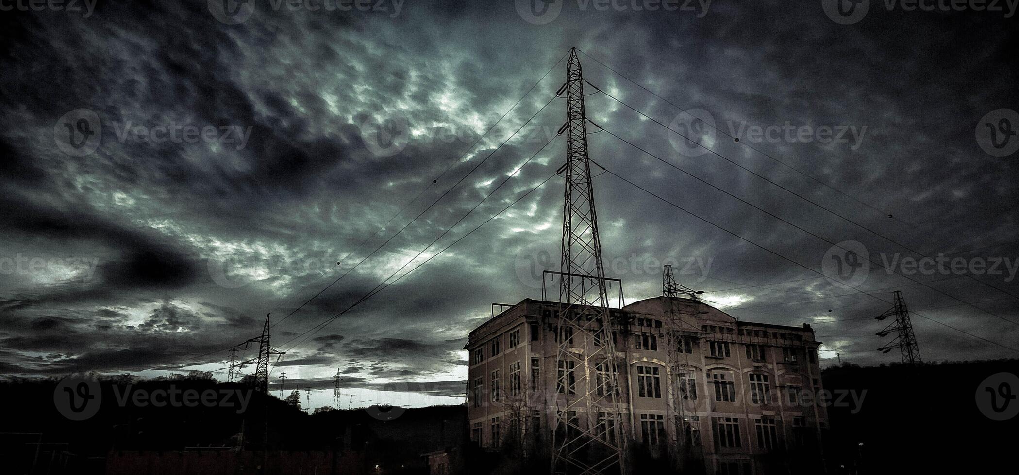 Electricity factory with long-abandoned high voltage cables. dark and noir setting with cloudy sky photo