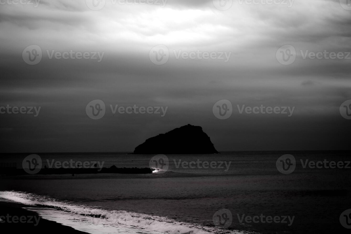 dark sea waves crash on the sandy coast of the Ligurian coast in a dark and noir setting photo