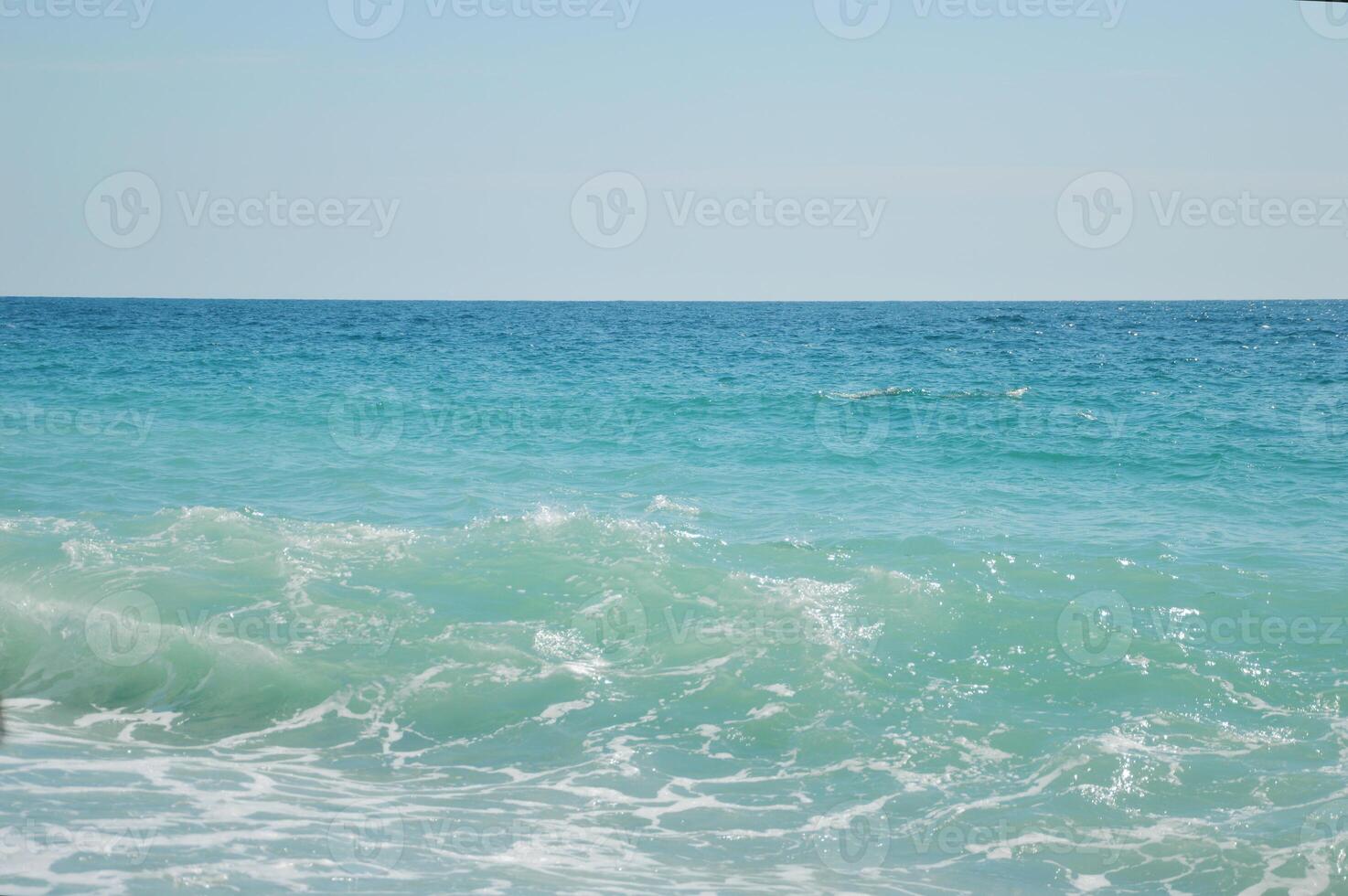 Sea, beautiful blue water with color transitions and splashes. Horizon line and clear sky. photo