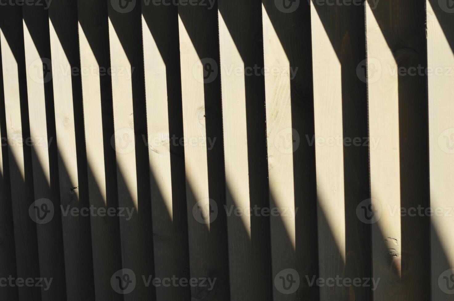 Dark brown wooden vertical slats, boards with sun glare. Element of decoration of the railing, facade of the building. photo