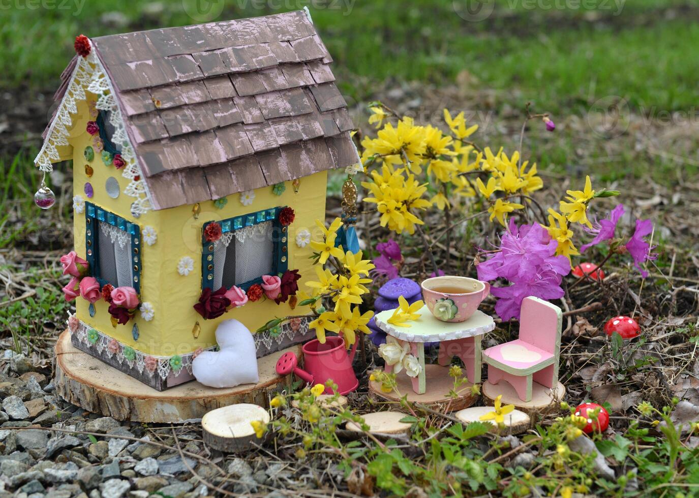Cute fairy doll house with spring flowers outside in the garden. Lovely miniature for greeting cards, wedding or birthday concept, real estate, downsizing, home ownership photo