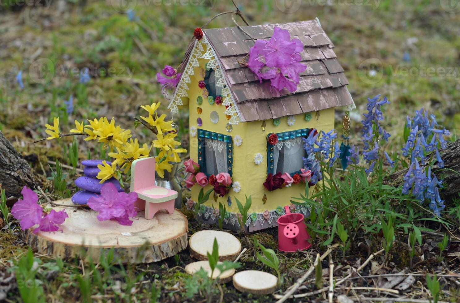 Cute fairy doll house with spring flowers outside in the garden. Lovely miniature for greeting cards, wedding or birthday concept, real estate, downsizing, home ownership photo