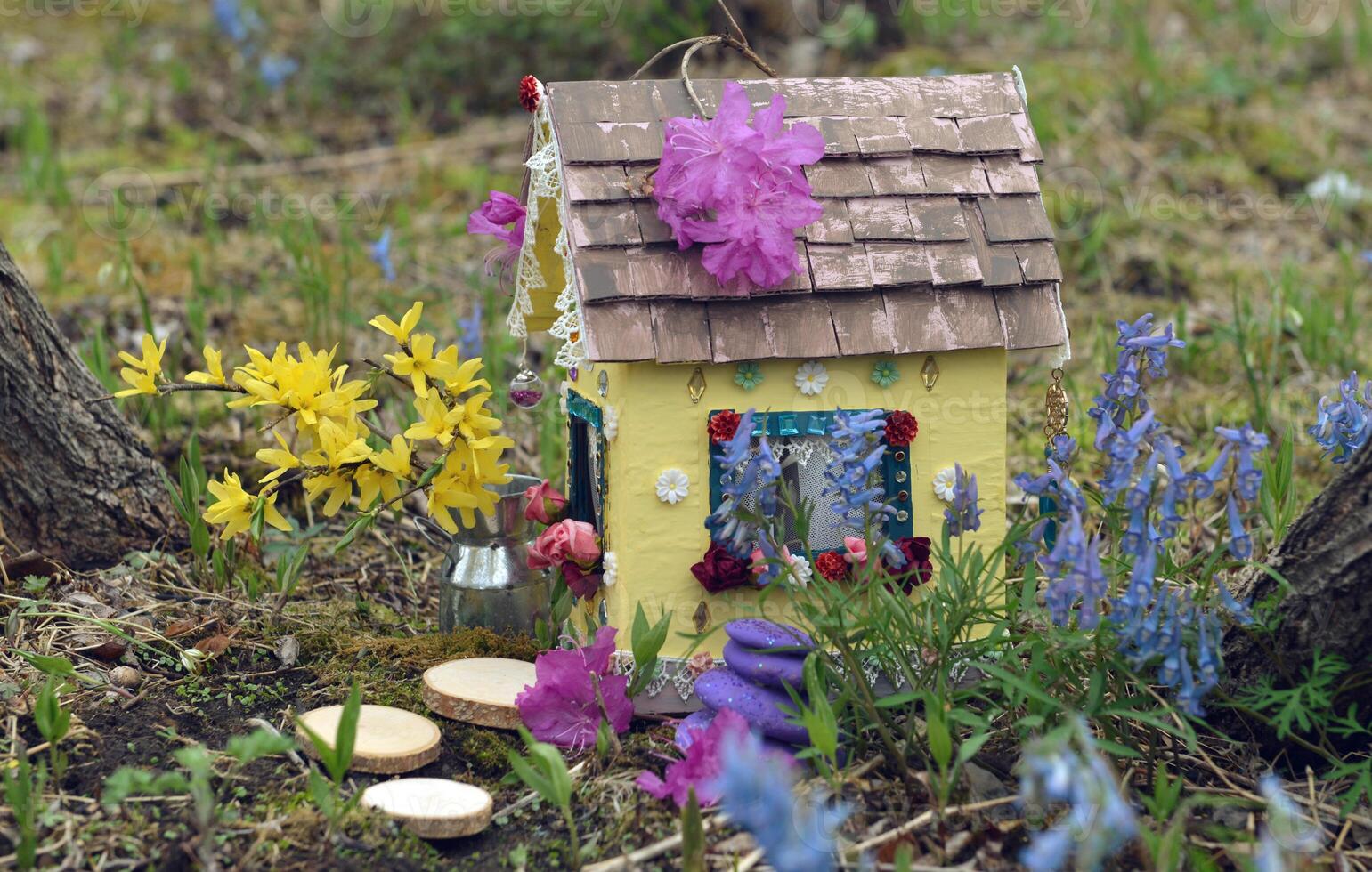 Cute fairy doll house with spring flowers outside in the garden. Lovely miniature for greeting cards, wedding or birthday concept, real estate, downsizing, home ownership photo