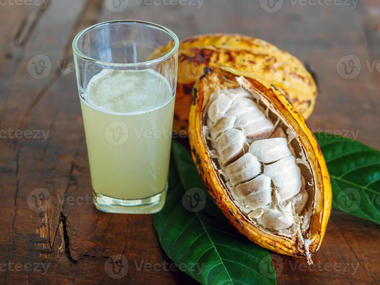 Fresh cacao water in glass and half sliced ripe yellow cacao pod with white cocoa seed, Cacao juice in glass on vintage wooden background photo