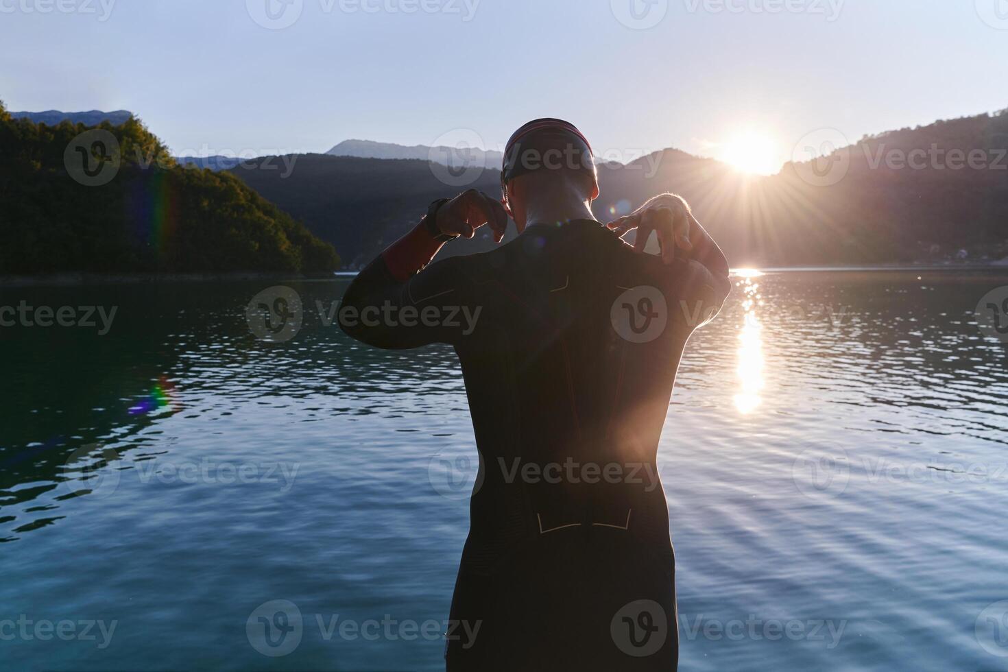 Authentic triathlon athlete getting ready for swimming training on lake photo