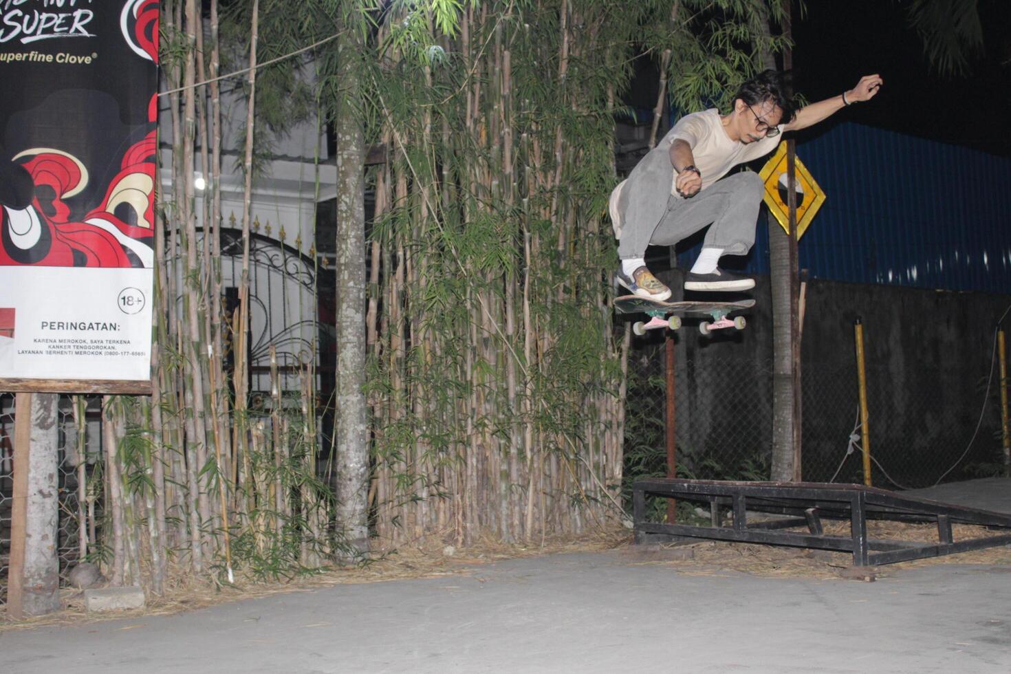Indonesia - Medan 01 August 2023 an asian man doing skateboard tricks on a ramp photo