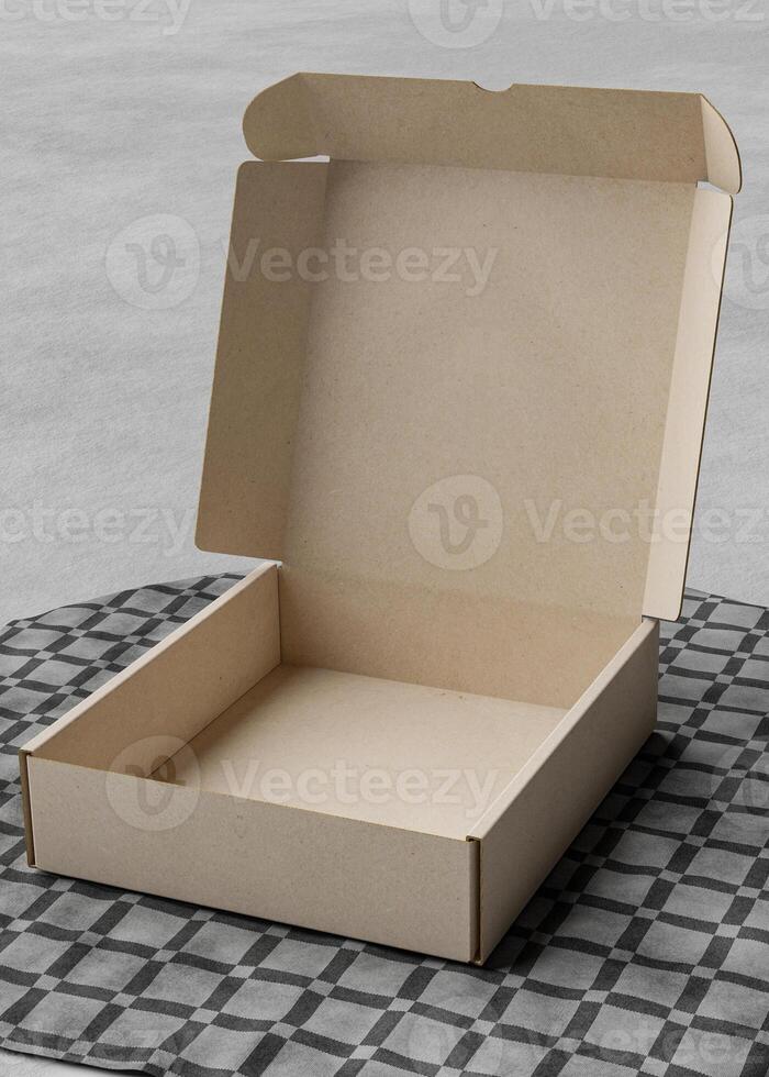 Opened Cardboard box on the table with a square tablecloth photo