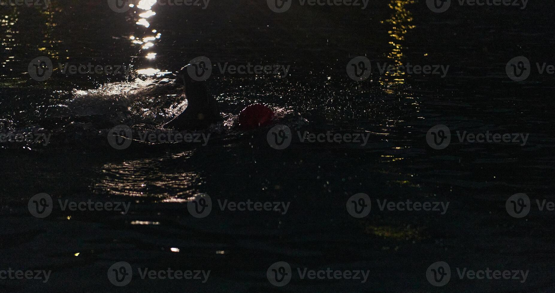 A determined professional triathlete undergoes rigorous night time training in cold waters, showcasing dedication and resilience in preparation for an upcoming triathlon swim competition photo