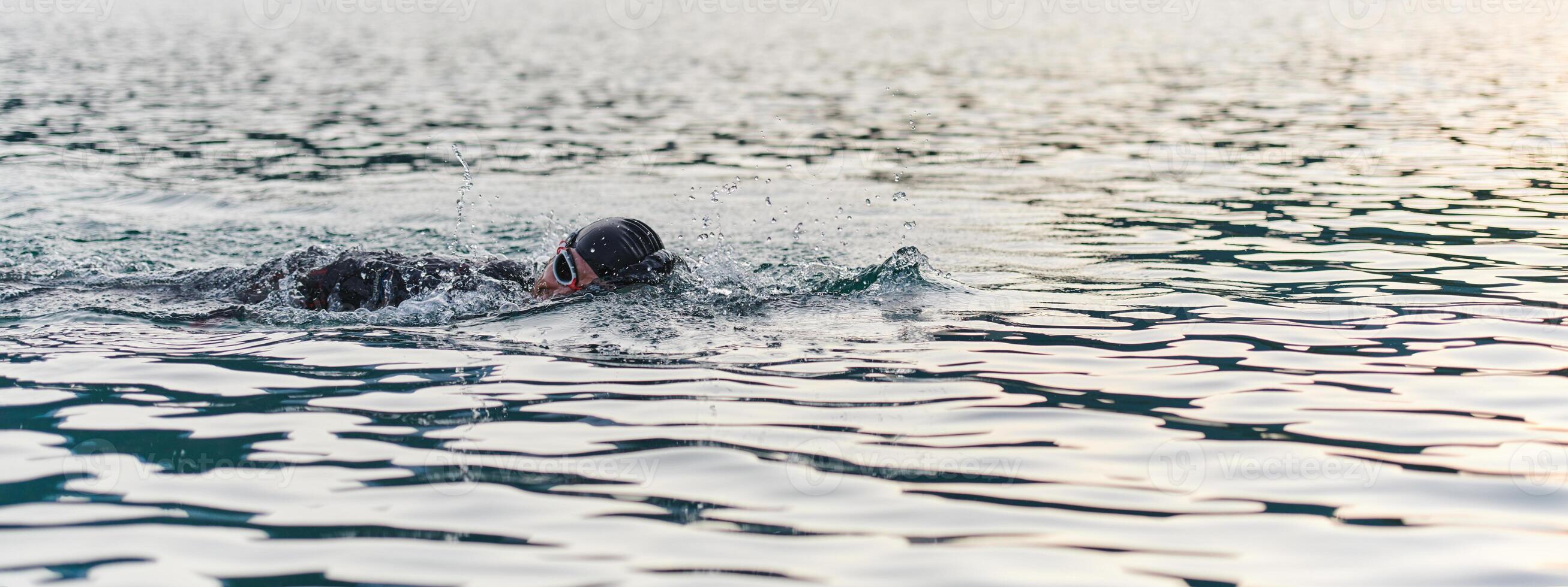 A professional triathlete trains with unwavering dedication for an upcoming competition at a lake, emanating a sense of athleticism and profound commitment to excellence. photo