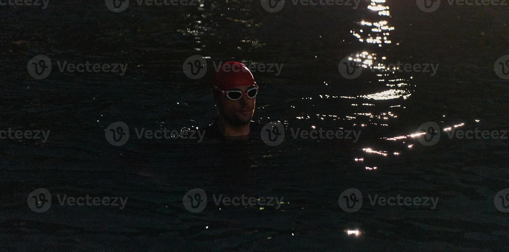A determined professional triathlete undergoes rigorous night time training in cold waters, showcasing dedication and resilience in preparation for an upcoming triathlon swim competition photo