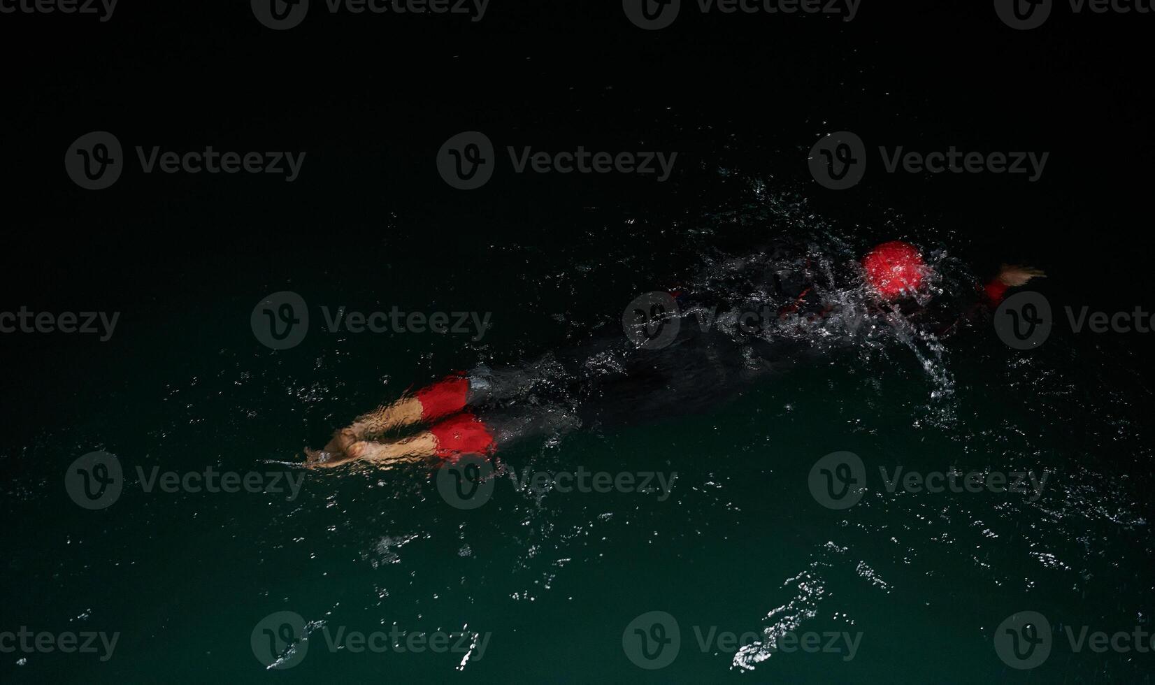 A determined professional triathlete undergoes rigorous night time training in cold waters, showcasing dedication and resilience in preparation for an upcoming triathlon swim competition photo