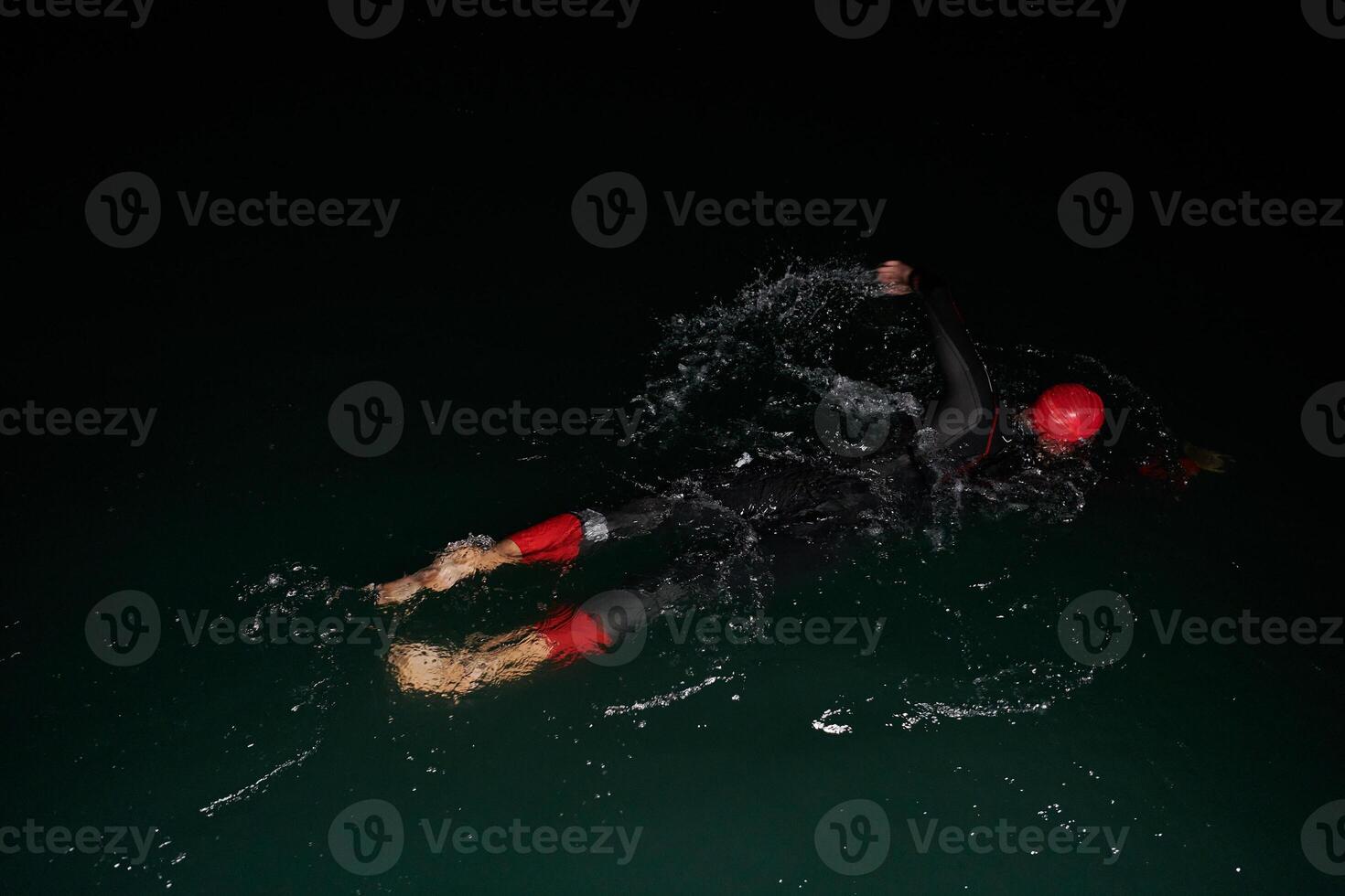 A determined professional triathlete undergoes rigorous night time training in cold waters, showcasing dedication and resilience in preparation for an upcoming triathlon swim competition photo
