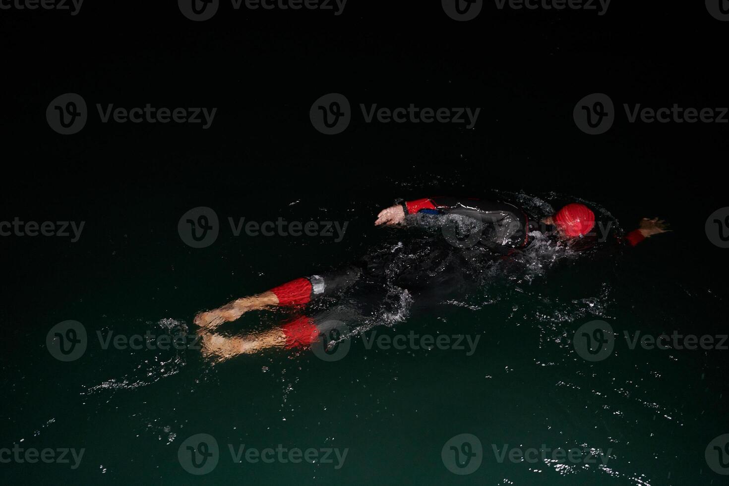 A determined professional triathlete undergoes rigorous night time training in cold waters, showcasing dedication and resilience in preparation for an upcoming triathlon swim competition photo