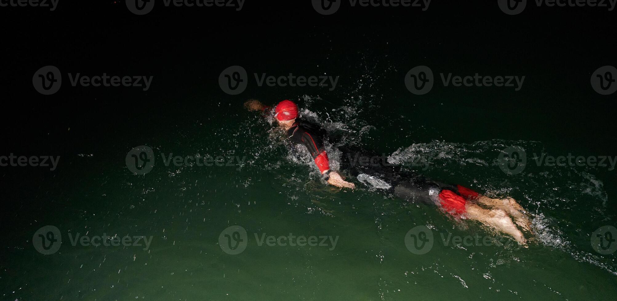 A determined professional triathlete undergoes rigorous night time training in cold waters, showcasing dedication and resilience in preparation for an upcoming triathlon swim competition photo