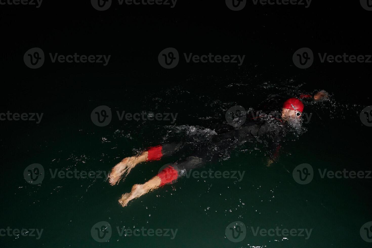A determined professional triathlete undergoes rigorous night time training in cold waters, showcasing dedication and resilience in preparation for an upcoming triathlon swim competition photo