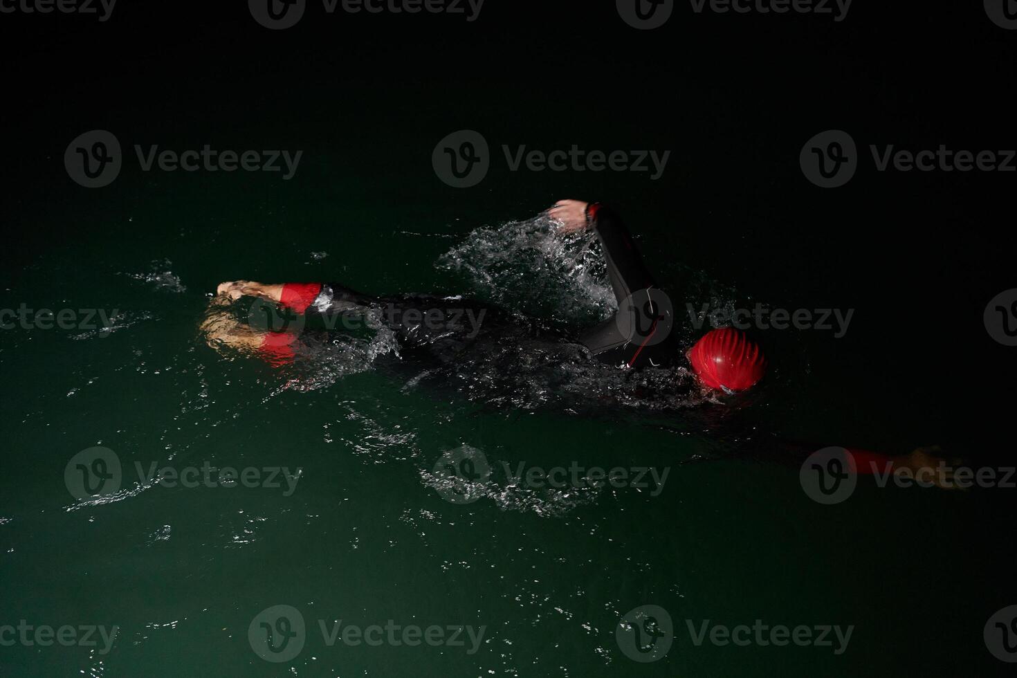 A determined professional triathlete undergoes rigorous night time training in cold waters, showcasing dedication and resilience in preparation for an upcoming triathlon swim competition photo