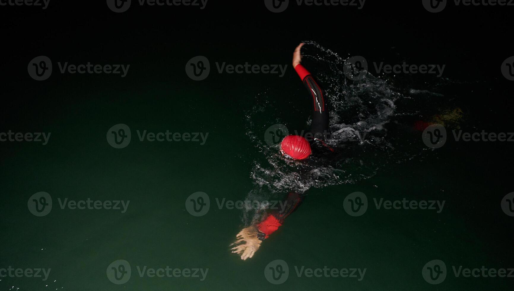 A determined professional triathlete undergoes rigorous night time training in cold waters, showcasing dedication and resilience in preparation for an upcoming triathlon swim competition photo
