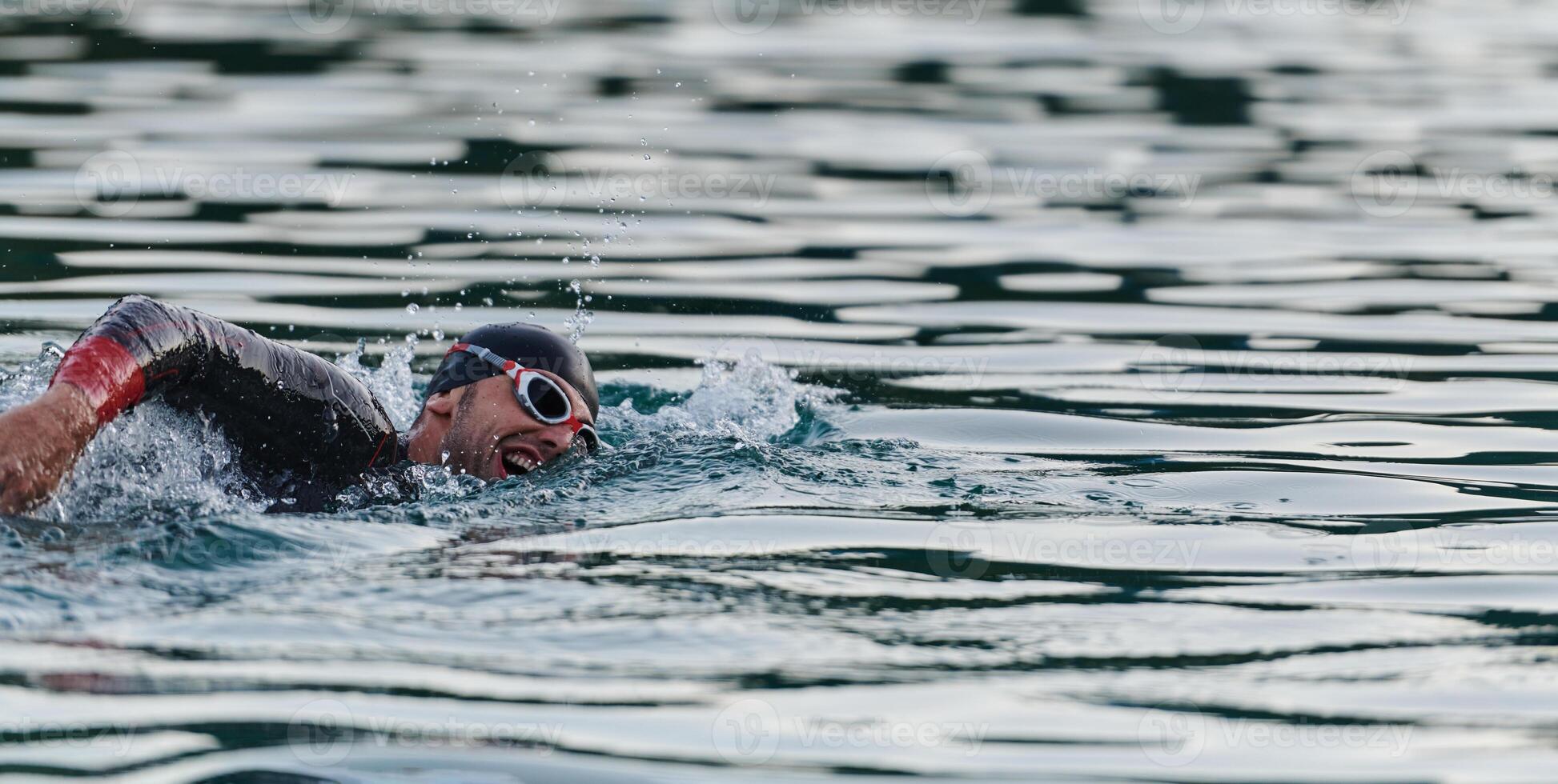 A professional triathlete trains with unwavering dedication for an upcoming competition at a lake, emanating a sense of athleticism and profound commitment to excellence. photo