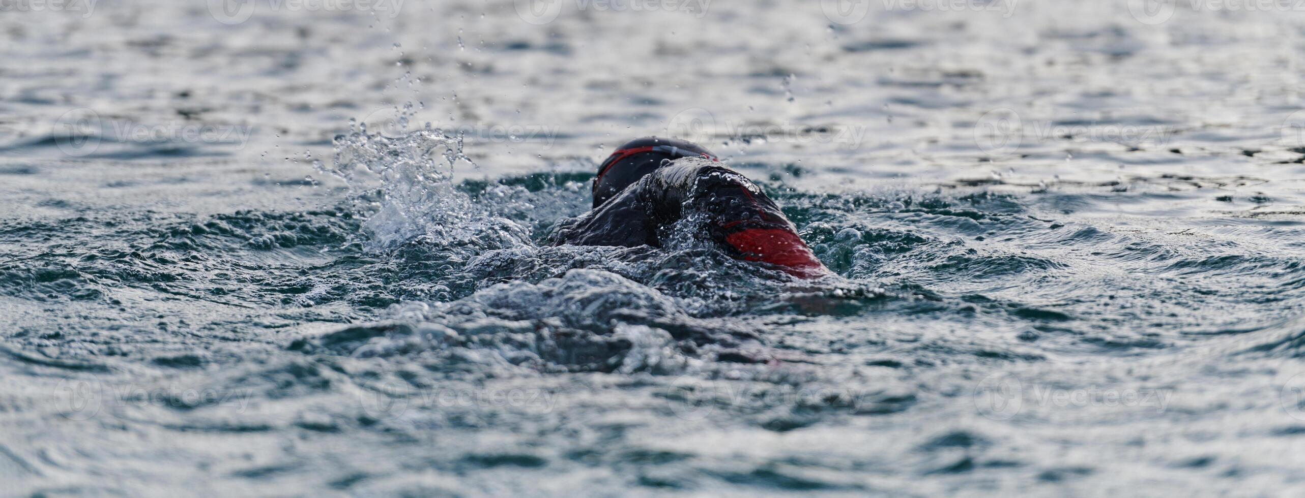 A professional triathlete trains with unwavering dedication for an upcoming competition at a lake, emanating a sense of athleticism and profound commitment to excellence. photo