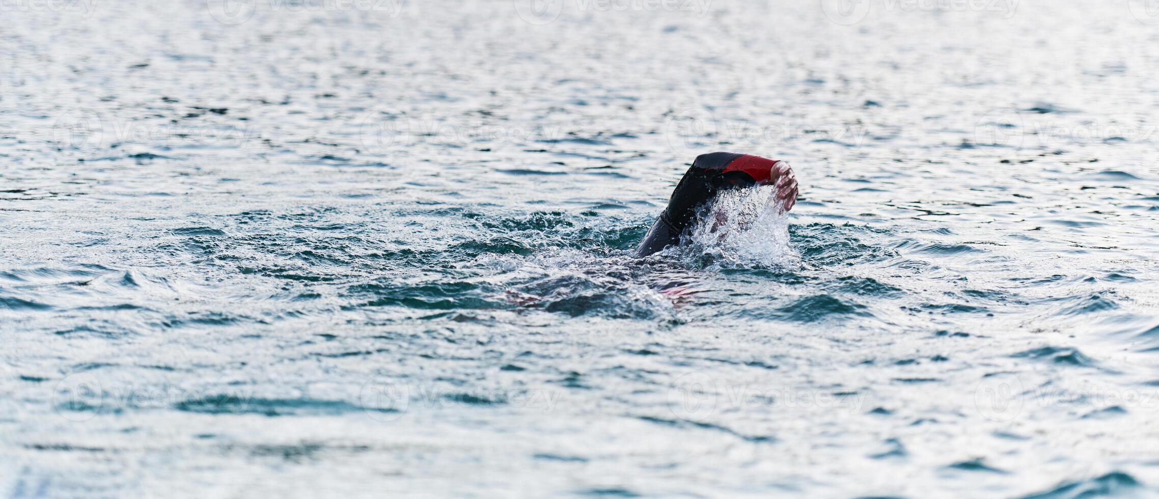A professional triathlete trains with unwavering dedication for an upcoming competition at a lake, emanating a sense of athleticism and profound commitment to excellence. photo