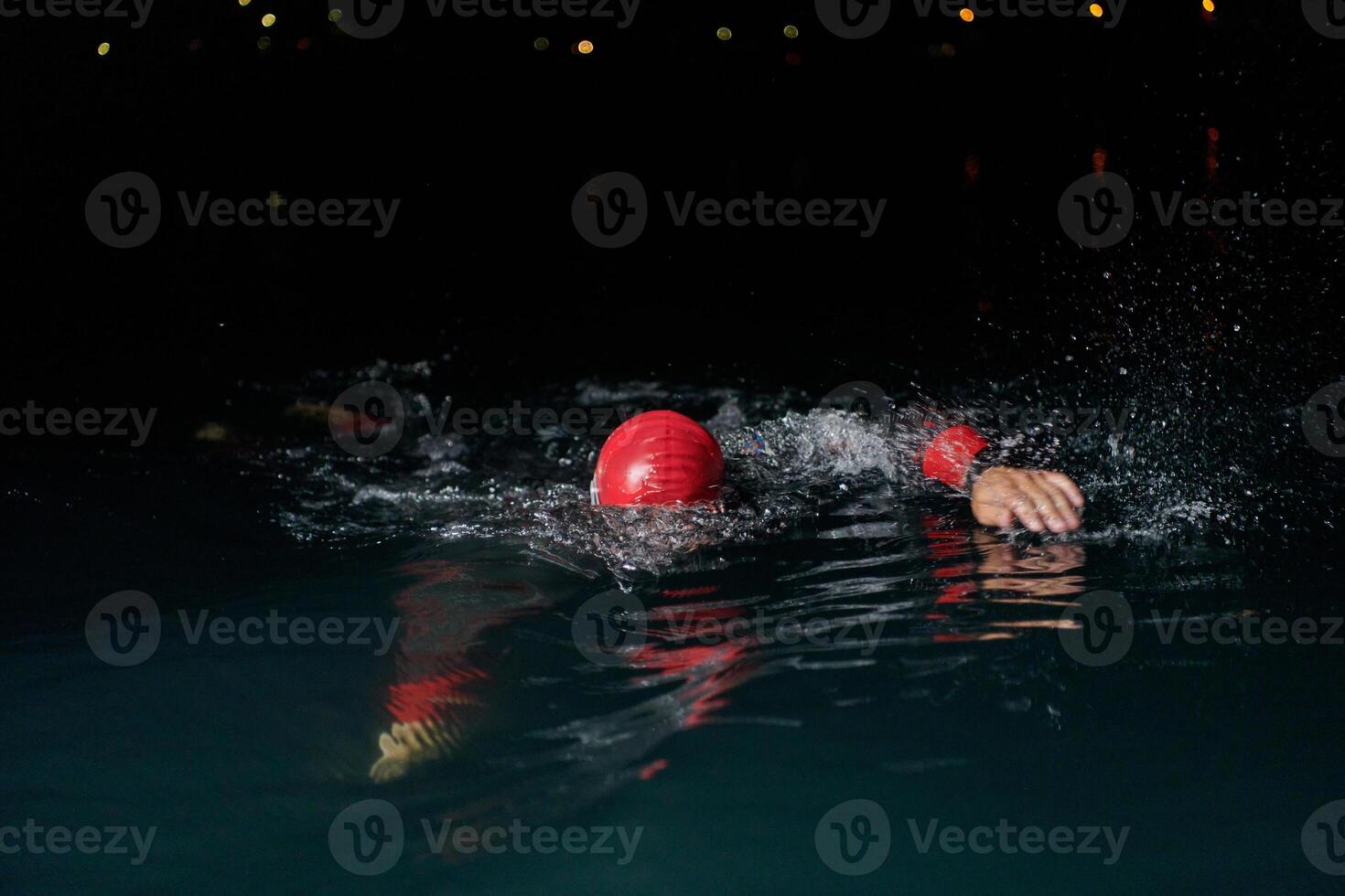 A determined professional triathlete undergoes rigorous night time training in cold waters, showcasing dedication and resilience in preparation for an upcoming triathlon swim competition photo