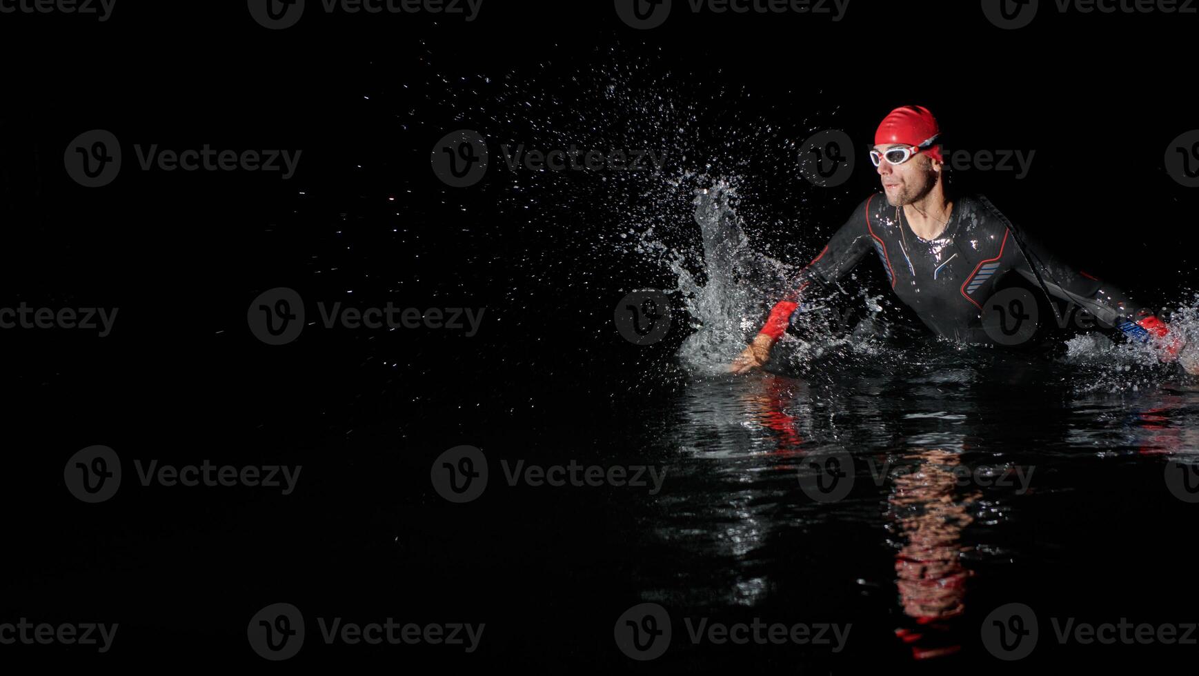 A determined professional triathlete undergoes rigorous night time training in cold waters, showcasing dedication and resilience in preparation for an upcoming triathlon swim competition photo