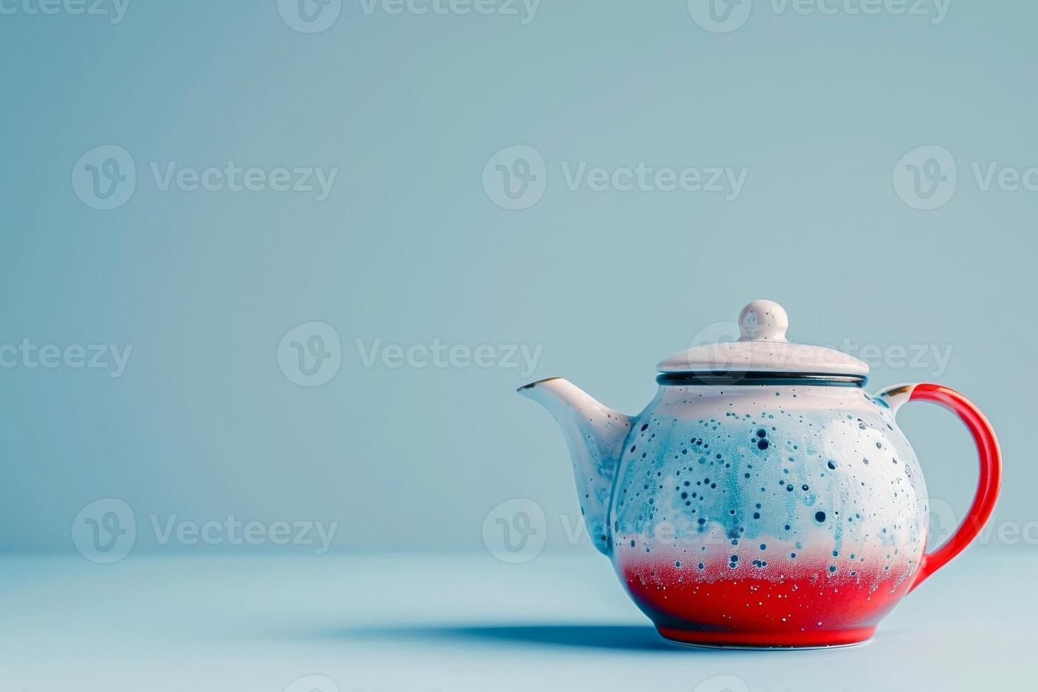 A quirky teapot painted in red, white, and blue, on a blue to white gradient background photo