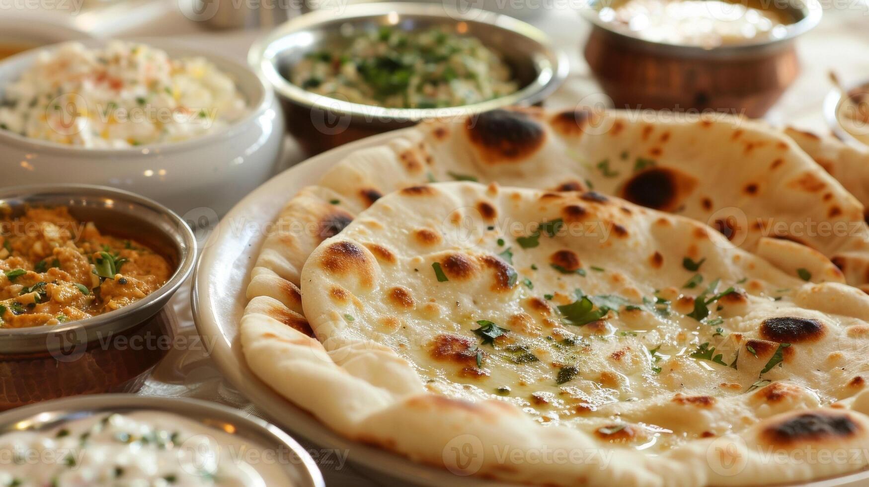 Plates of fluffy goldenbrown flatbread known as naan are p alongside bowls of creamy hummus and tangy tzatziki for dipping photo