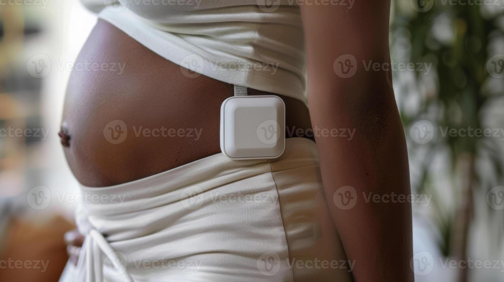 A closeup of a small rectangular device attached to the mothers hip. The device tracks the mothers posture and sends reminders to sit and stand properly to avoid discomfor photo