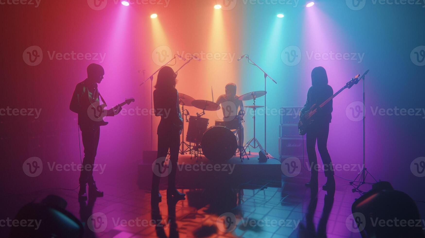 A group of four band members huddled together on a small stage drenched in colorful lights. The lead singer stares passionately into the audience as she sings while the drumme photo