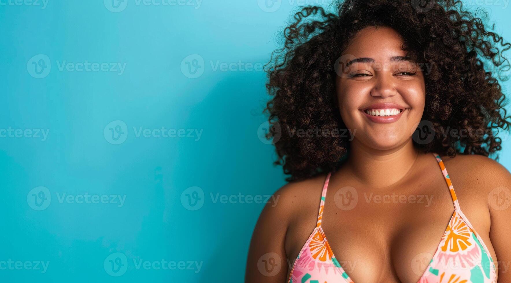 A plus size black afro-american bikini model with curly hair is smiling and wearing a bikini top photo