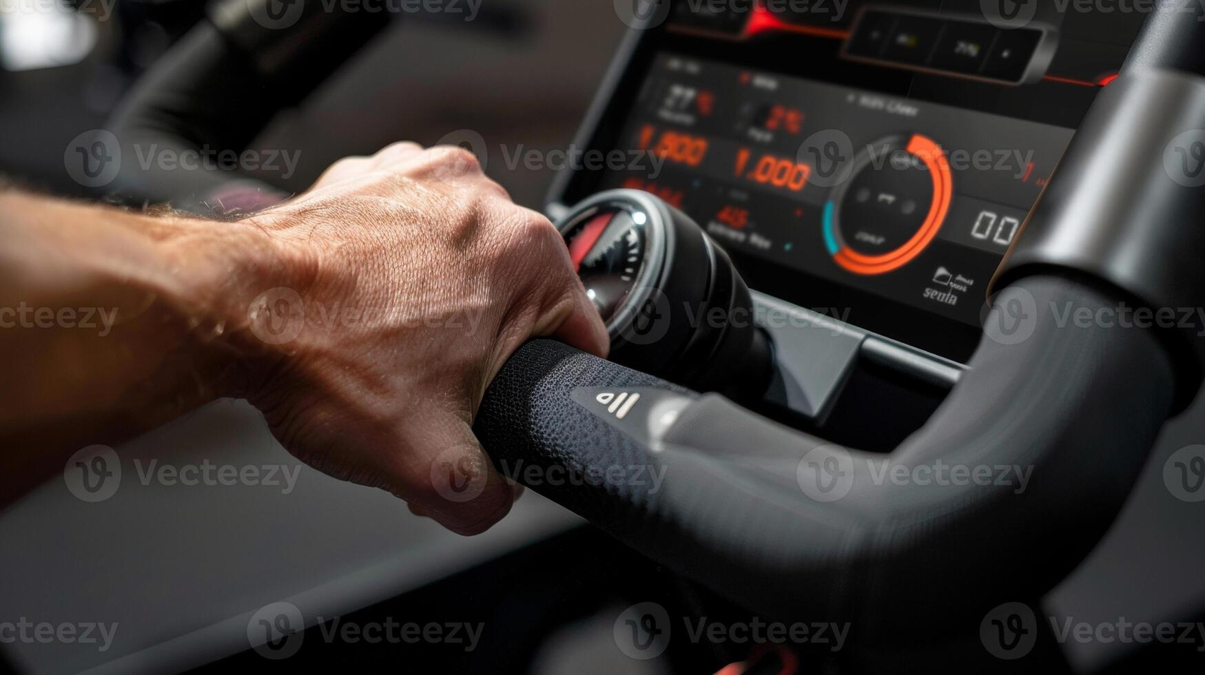 A closeup of a hand gripping onto the handlebars of an advanced indoor cycling bike with a digital display showing realtime metrics such as cadence and resistance level photo