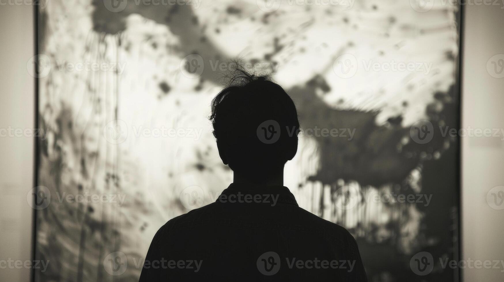 With face hidden a person stands in front of the evocative artwork seemingly absorbed by the powerful effect of the artists . photo