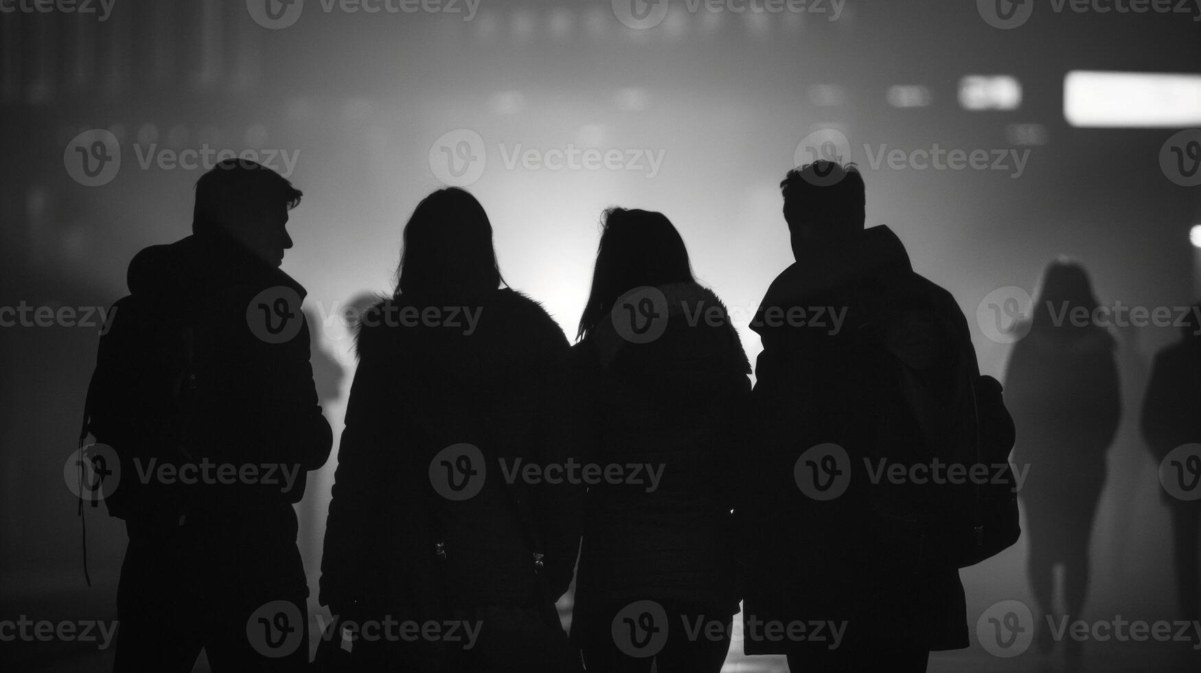 The silhouettes of four people stand in a huddle postures tense and ready for action. . photo
