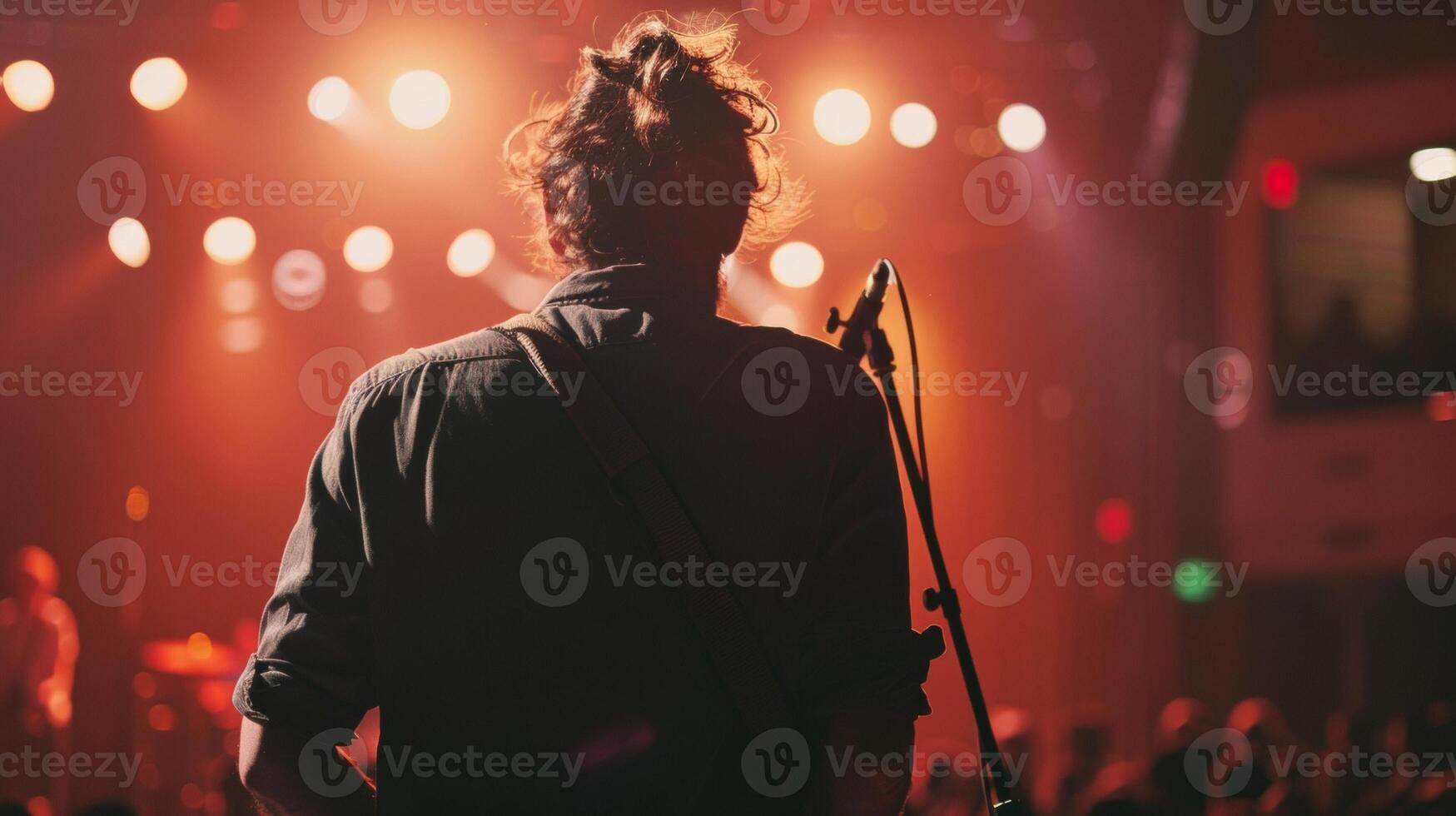 A musician stands on stage back to the audience as they pour heart and soul into performance. . photo