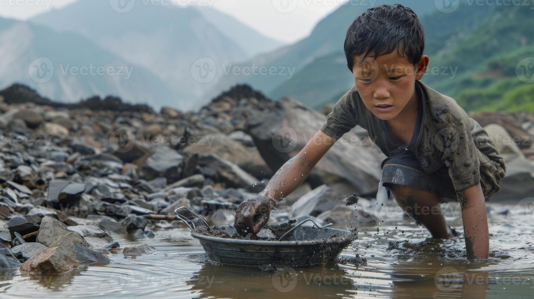 A young boy no more than twelve years old stands kneedeep in murky water his small hands sifting through a sieve filled with grey sludge. As he carefully picks through the debris his photo