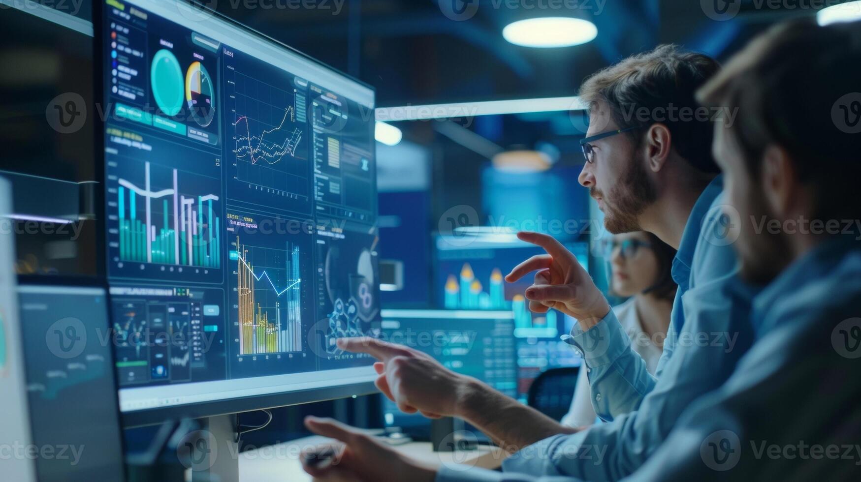 At a modern office a group of colleagues gather around a central computer screen eagerly discussing the latest technological breakthrough. Charts graphs and diagrams are displayed photo
