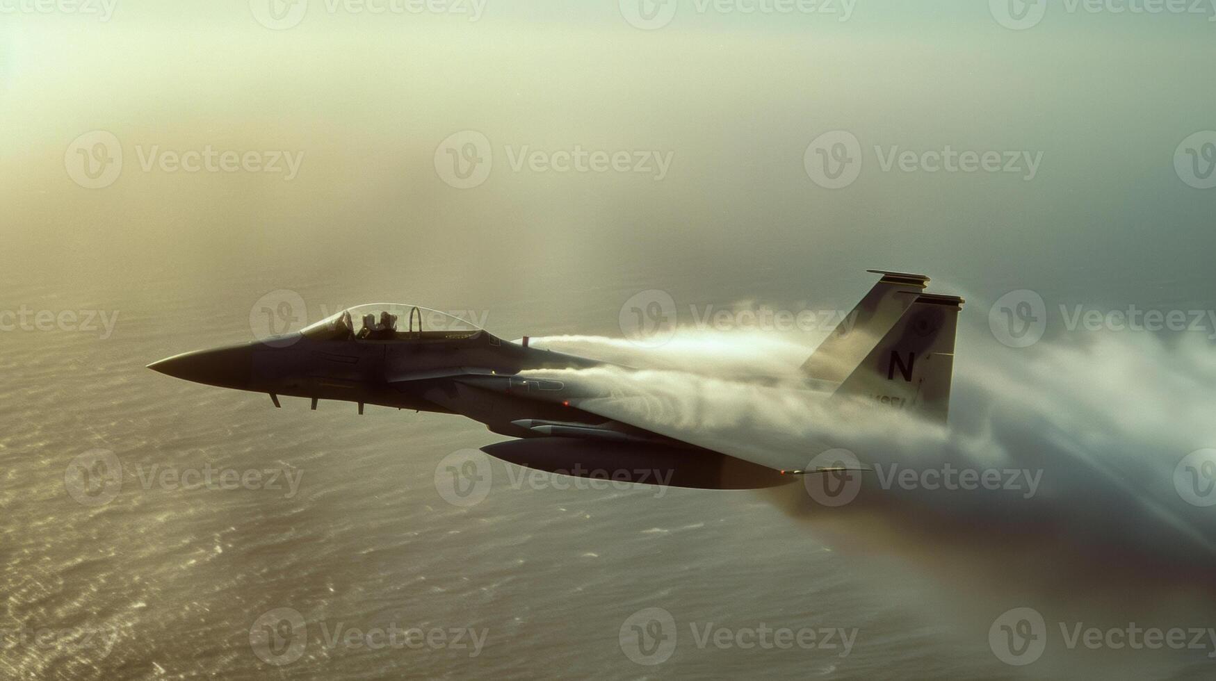A military fighter jet zooms through the air leaving a trail of vapor in its wake as it makes a quick ascent photo