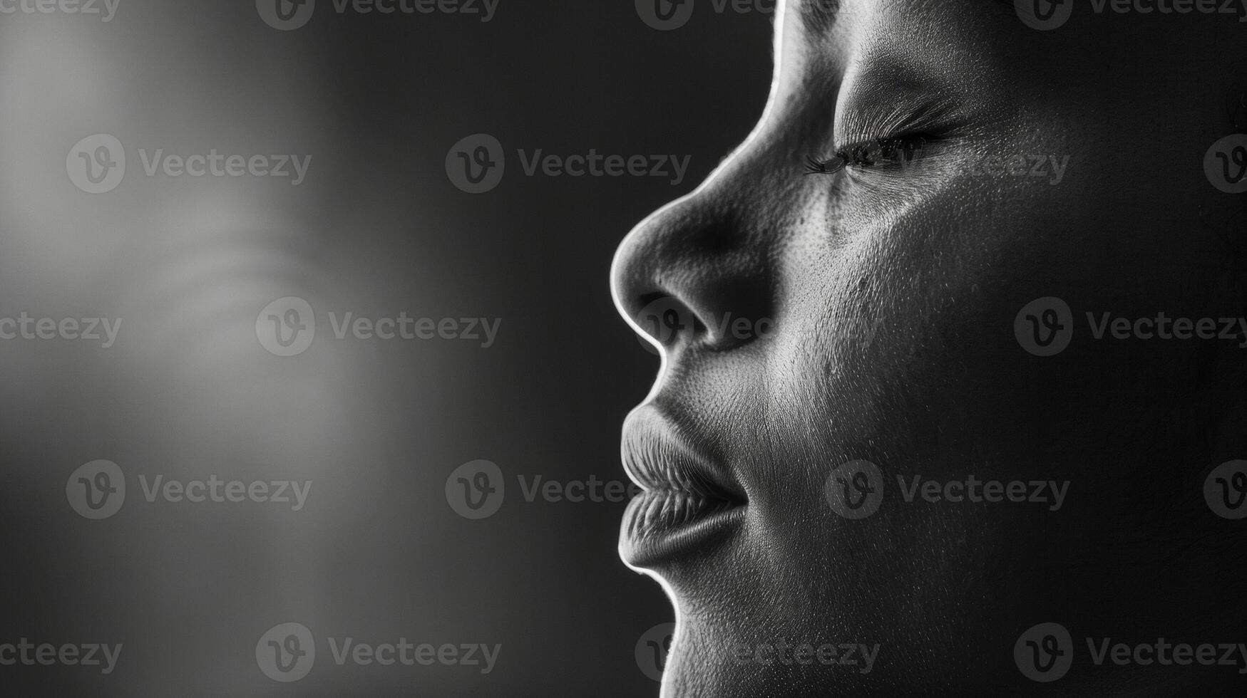 A black and white image of a persons face in profile their eyes closed and a peaceful expression on their face. Soft light illuminates their face creating a serene and introspectiv photo