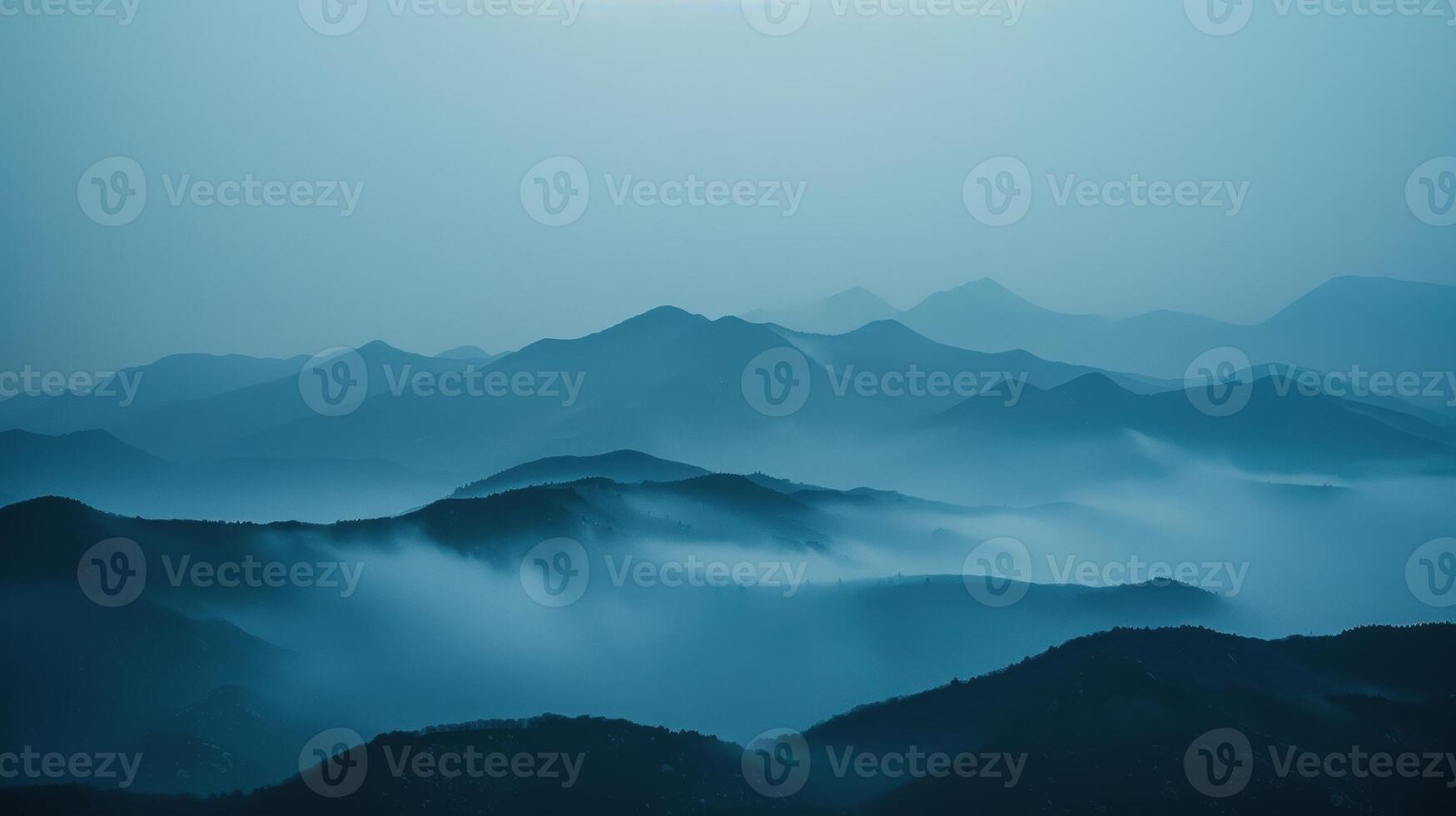 The mountains appearing faded and distant obscured by the thick fog photo