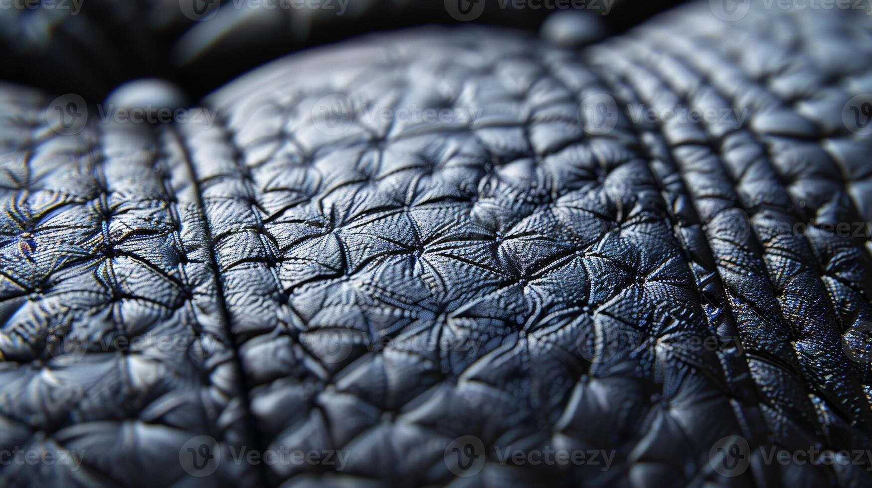 A macro shot of the shiny smooth surface of a black leather sofa featuring intricate stitching and subtle grain patterns photo