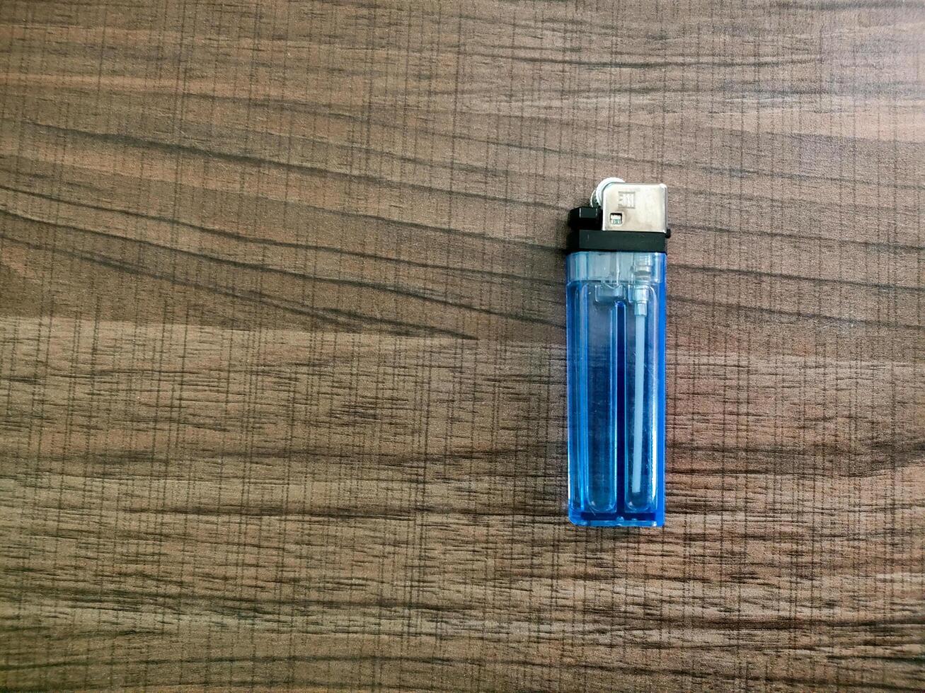 Blue gas lighter on wooden table photo